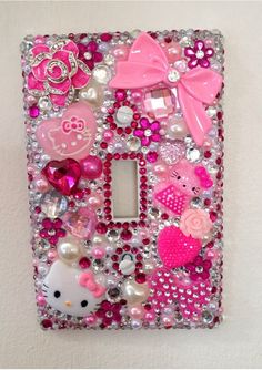 a hello kitty light switch plate cover is decorated with pink, white and silver jewels