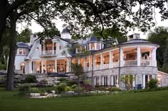 a large white house sitting in the middle of a lush green field with lots of trees