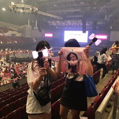 two girls are holding up their cell phones in front of the audience at a concert