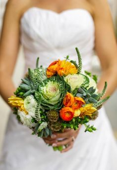 a bride holding a bouquet of flowers and succulents