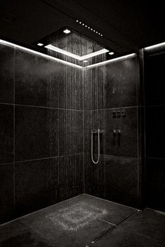 a shower head in the middle of a black and white photo with lights above it