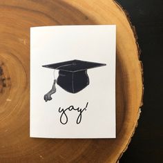 a piece of paper with a graduation cap and the word gay on it sitting on top of a tree stump