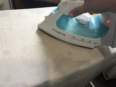 a person ironing an iron on top of a white sheet with blue and yellow buttons