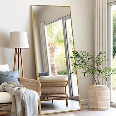 a living room filled with furniture and a large mirror next to a plant in a vase