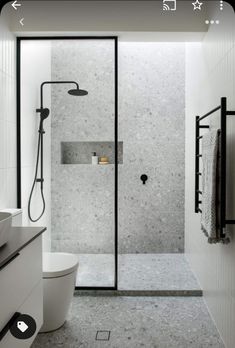 a bathroom with a walk in shower next to a white toilet and black accents on the walls