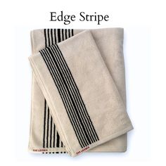 two towels with black and white stripes on them, one is folded up to show the edge