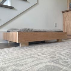 a bed sitting on top of a wooden platform next to a stair case in a living room