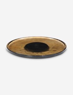 a black and gold plate sitting on top of a white surface with an oval hole in the center