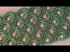 a close up of a green crochet with pearls on it