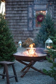 an outdoor fire pit surrounded by evergreens and christmas trees is shown on instagram