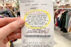 a person is holding up a ticket for an event in a clothing store with clothes on racks