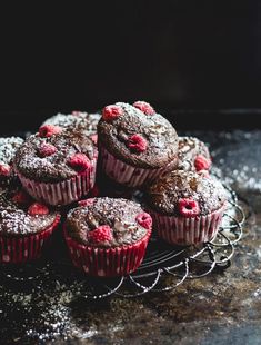 chocolate muffins with raspberries on a wire rack and powdered sugar