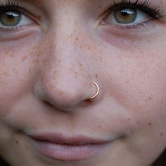 a close up of a person with freckles on their nose and nose ring