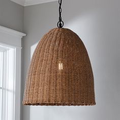 a wicker light fixture hanging from a ceiling in a room with white walls and windows