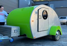 a woman standing next to a green and white trailer