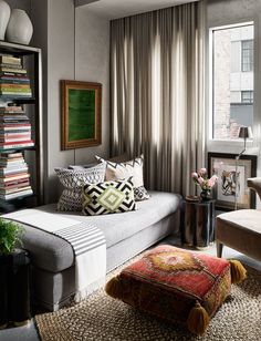 a living room filled with lots of furniture and bookshelves next to a window