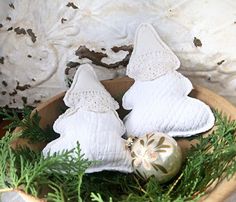 three white christmas ornaments in a wooden bowl