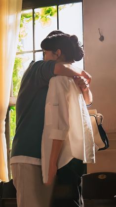 two people embracing each other in front of a window with sunlight coming through the windows