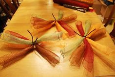 four orange and green mesh bows on a wooden table in a room with other furniture