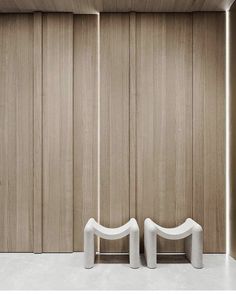 two white chairs sitting next to each other in front of wooden wall paneled walls