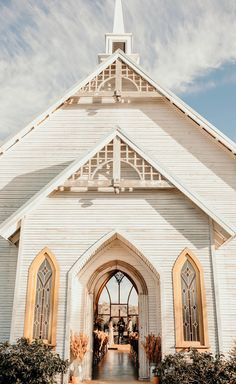 the front entrance to a white church with an arched doorway and steeple on top