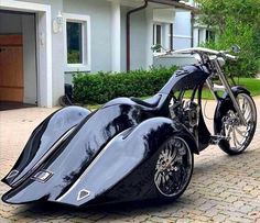 an unusual motorcycle is parked in front of a house