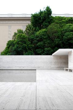 an empty concrete courtyard with benches and trees in the background