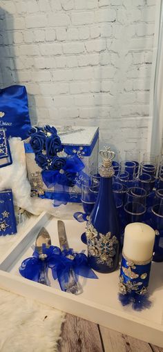 a table topped with lots of blue and silver items next to a white brick wall