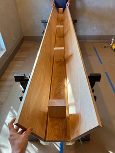 a man standing on top of a wooden bench in a room with hard wood flooring