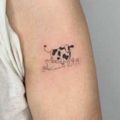 a small black and white cow tattoo on the left upper half of the right arm