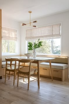 a dining table with four chairs and a bench in front of it, next to a window