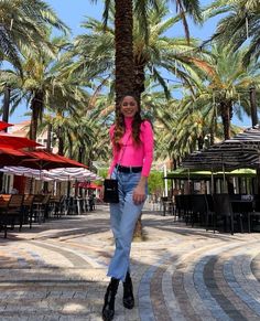 a woman standing next to a palm tree