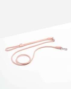 a pink cord on a white surface with an earphone attached to the end of it