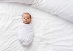 a baby laying on top of a white bed covered in blankets and pillows with the word pinterest above it