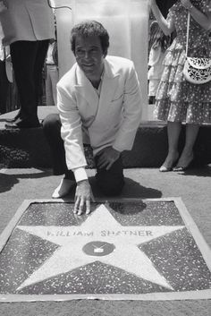 a man kneeling down next to a star on the hollywood walk of fame