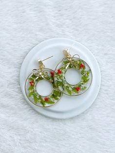 two green and red hoop earrings sitting on top of a white plate next to each other