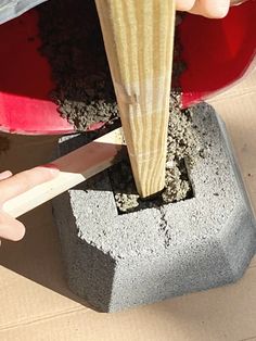 someone is using a large knife to cut the wood off of a cement planter