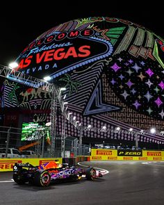 a red bull racing car in front of the las vegas sign at night with lights on