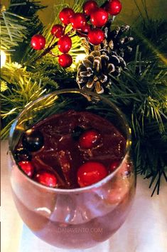 a drink in a glass with cherries and pine cones