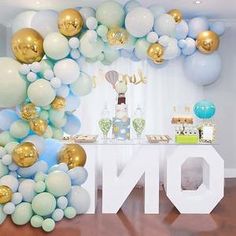 balloons and streamers are on the table for a first birthday party in blue, gold and white