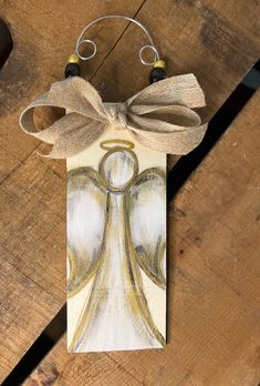 an angel ornament hanging on a wooden table with a string attached to it