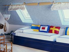 an attic bedroom with two beds and three chairs in front of the windows, along with other furniture