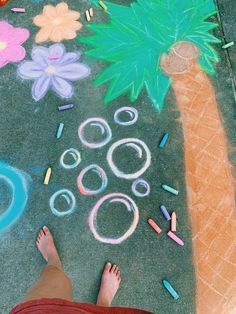 a person standing in front of a chalk drawing on the ground with colored pencils