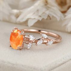 an orange ring sitting on top of a white flowered cloth next to some flowers