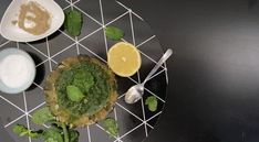 a plate topped with different types of food on top of a black table next to bowls and spoons