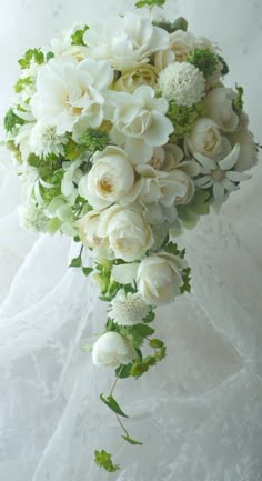 a bridal bouquet with white flowers and greenery hanging from it's side