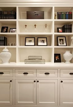 a white bookcase filled with lots of books next to a vase and pictures on top of it