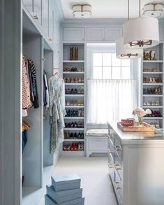 a walk - in closet with white cabinets and drawers, two lamps hanging from the ceiling