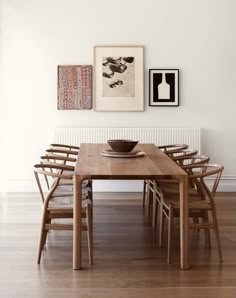 a wooden table with chairs and pictures on the wall above it in a dining room