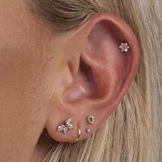 a close up of a woman's ear with three small flower studs on it